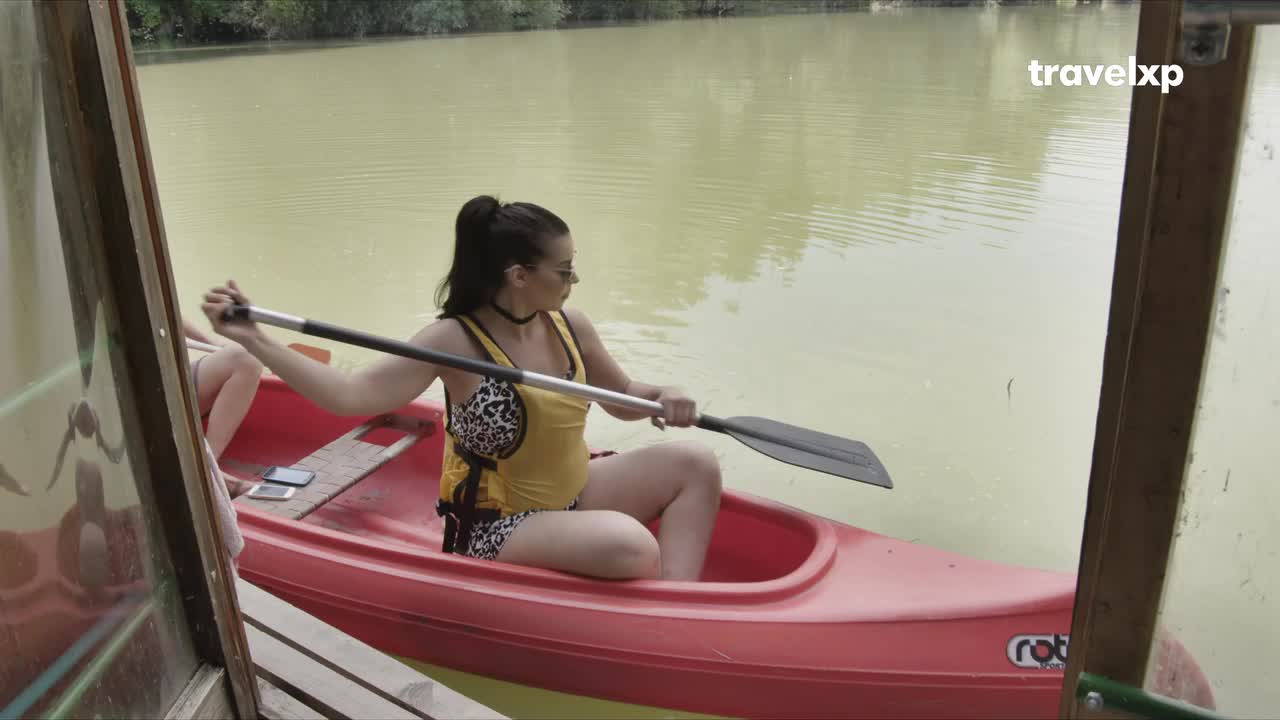 A woman in a yellow top and patterned shorts grips a paddle, ready to push off from the wooden dock. The canoe glides on calm, murky water, hinting at a tranquil escape. A woman in a yellow top and patterned shorts grips a paddle, ready to push off from the wooden dock. The canoe glides on calm, murky water, hinting at a tranquil escape.