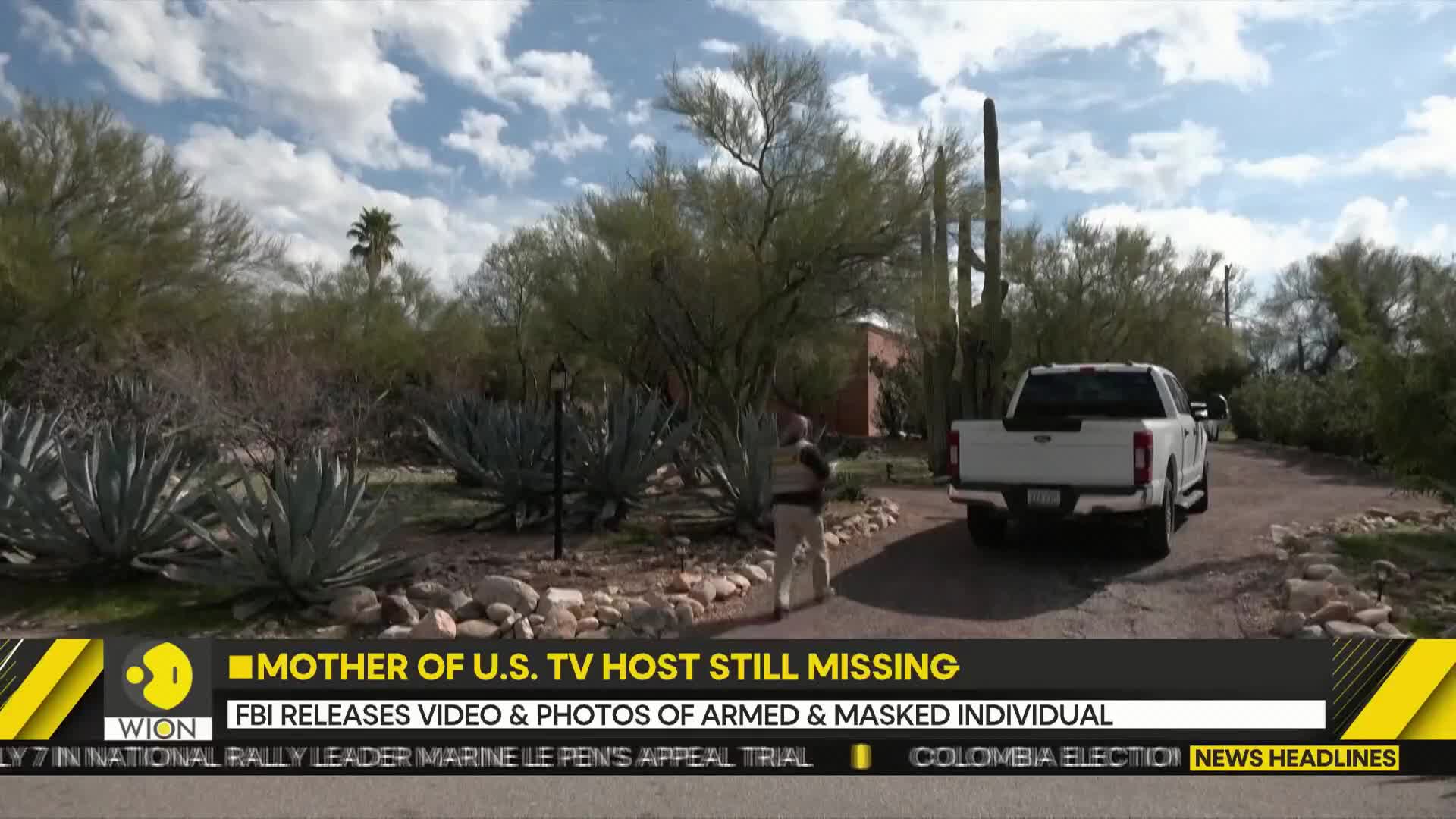 A person in a light-colored uniform walks away from a white pickup truck parked on a gravel driveway. The truck is facing away from the camera, its taillights visible.