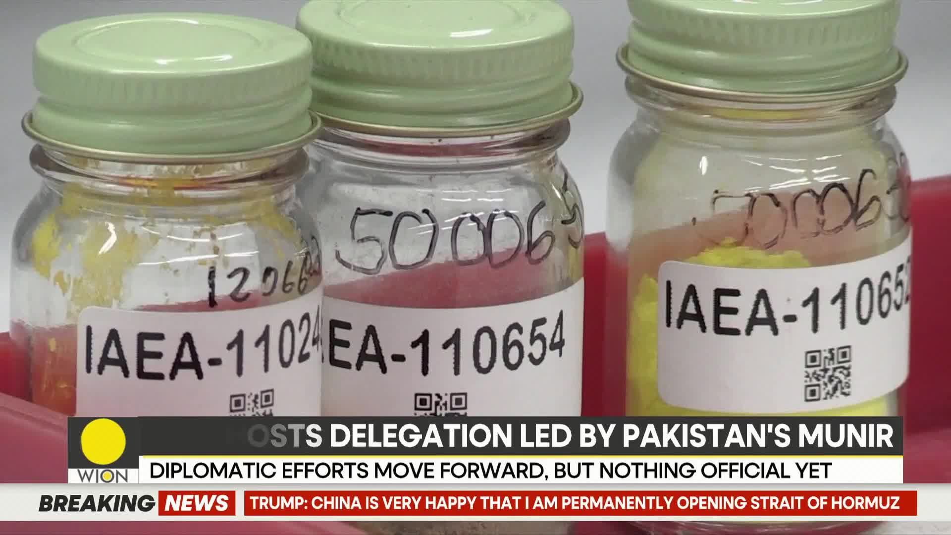 Three glass jars with light green caps sit side-by-side, each containing a different colored powder. Labels on the jars read "IAEA-11024," "EA-110654," and "IAEA-11065." A news ticker at the bottom displays "WION DIPLOMATIC EFFORTS MOVE FORWARD, BUT NOTHING OFFICIAL YET."