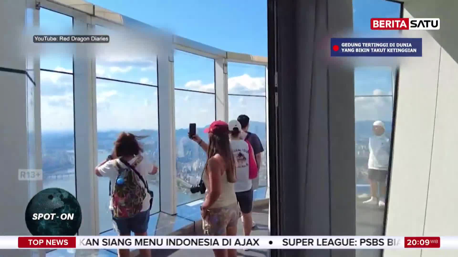 A woman in a red cap holds up her phone, capturing a selfie with the sprawling cityscape behind her. Beside her, others stand at the floor-to-ceiling windows, taking in the view from this Indonesian skyscraper. A woman in a red cap holds up her phone, capturing a selfie with the sprawling cityscape behind her. Beside her, others stand at the floor-to-ceiling windows, taking in the view from this Indonesian skyscraper.