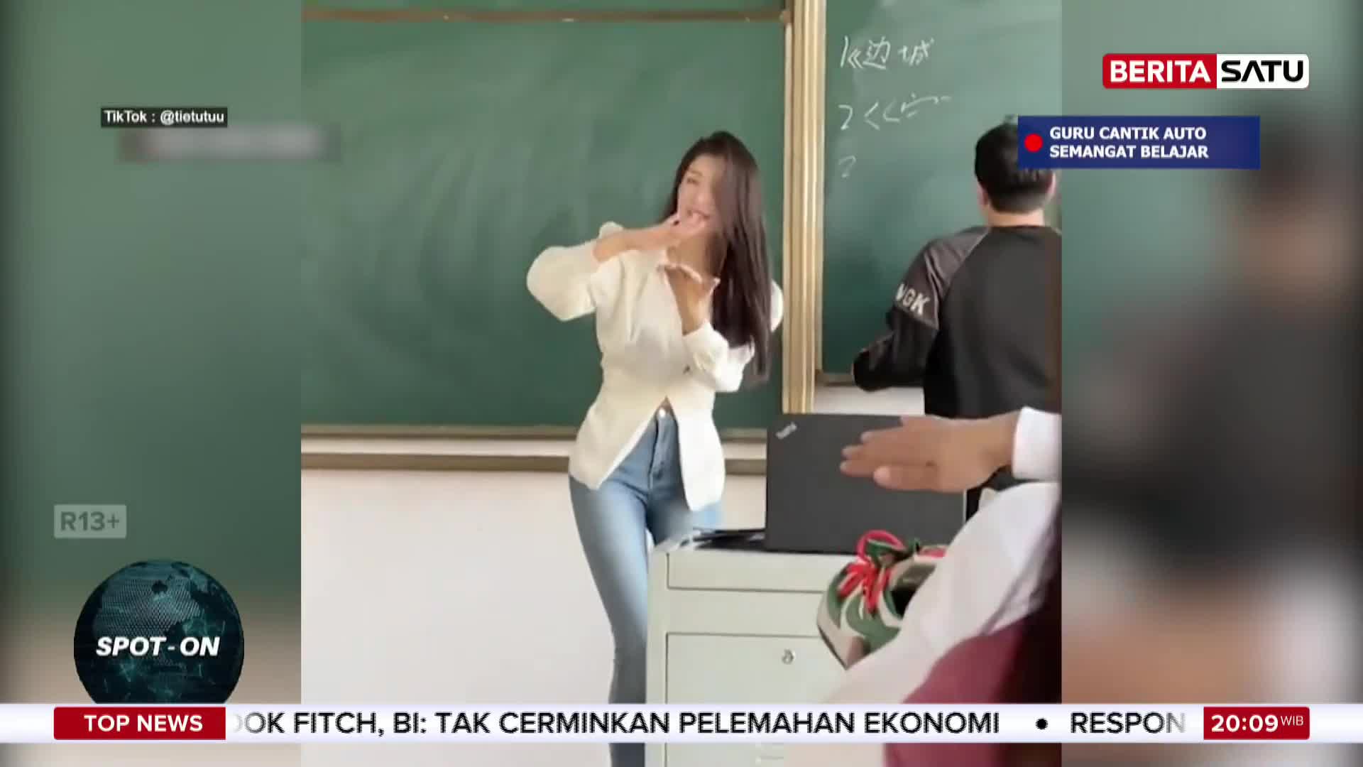 A young woman in a white top and jeans gestures animatedly in front of a blackboard, as if teaching. A BeritaSatu overlay indicates this is a report from Indonesia about an engaging teacher.