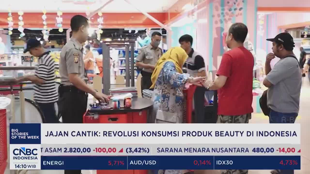 Two uniformed officers stand near a counter where a woman in a yellow hijab is interacting with a man in a red shirt. A man in a striped shirt is also visible behind the counter, looking down at his work.