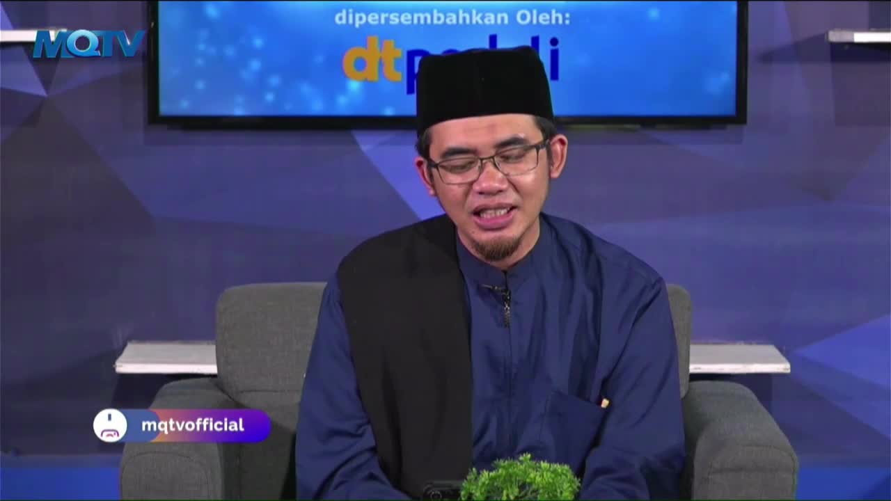 A man in a black cap and glasses is speaking, his mouth open as he looks towards the camera. The MQTV logo is visible in the corner, and a screen behind him displays text.
A man in a black cap and glasses is speaking, his mouth open as he looks towards the camera. The MQTV logo is visible in the corner, and a screen behind him displays text.