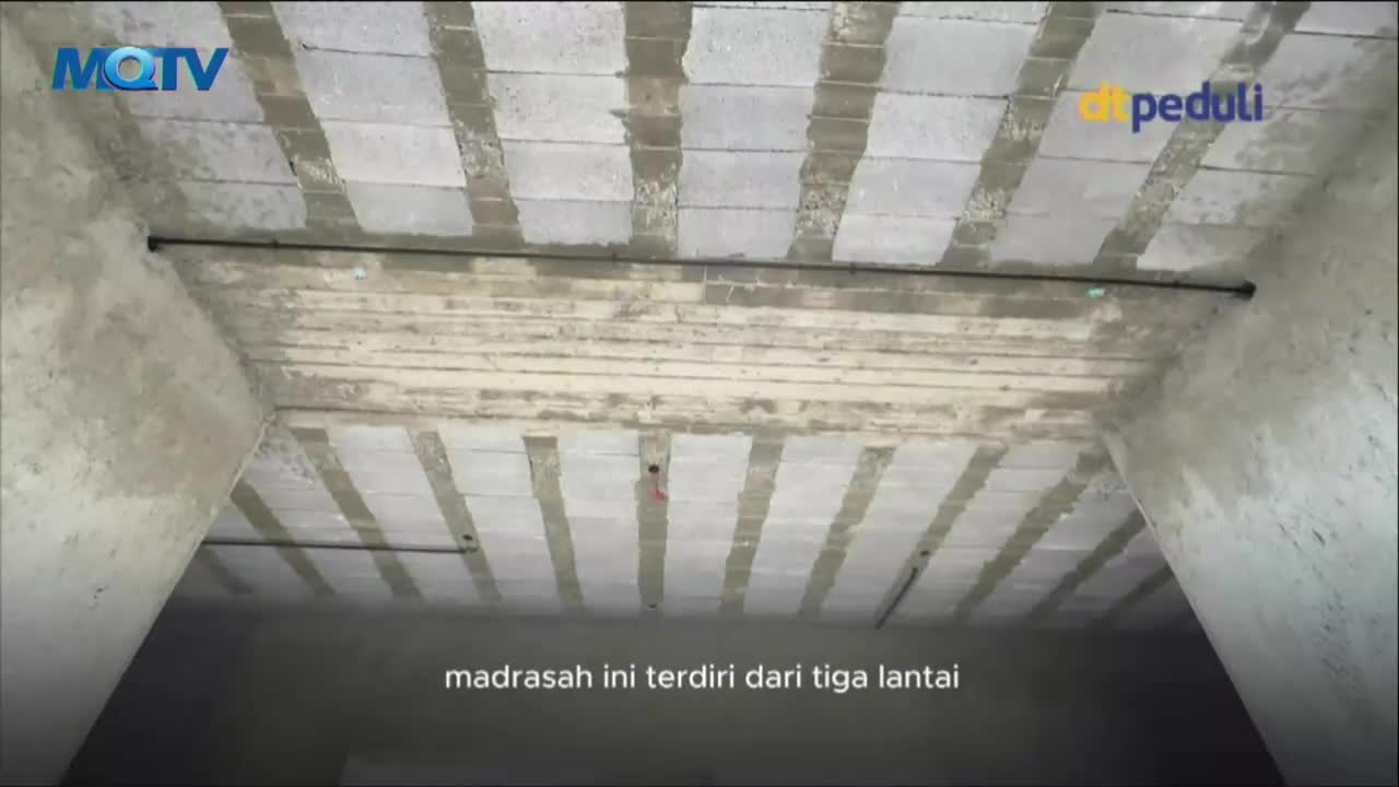 The camera angle looks up at a concrete ceiling, showing the bare structure of a building. The MQTV logo is visible in the corner, and the Indonesian text at the bottom describes the building as a three-story madrasah.
The camera angle looks up at a concrete ceiling, showing the bare structure of a building. The MQTV logo is visible in the corner, and the Indonesian text at the bottom describes the building as a three-story madrasah.
