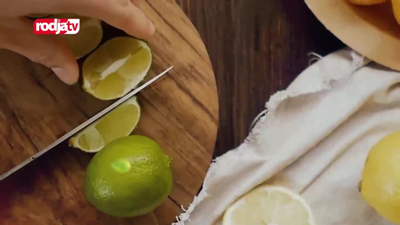 A hand guides a knife through a lime on a wooden board, while other limes and lemons rest on a white cloth. The Rodja TV logo is visible in the corner.