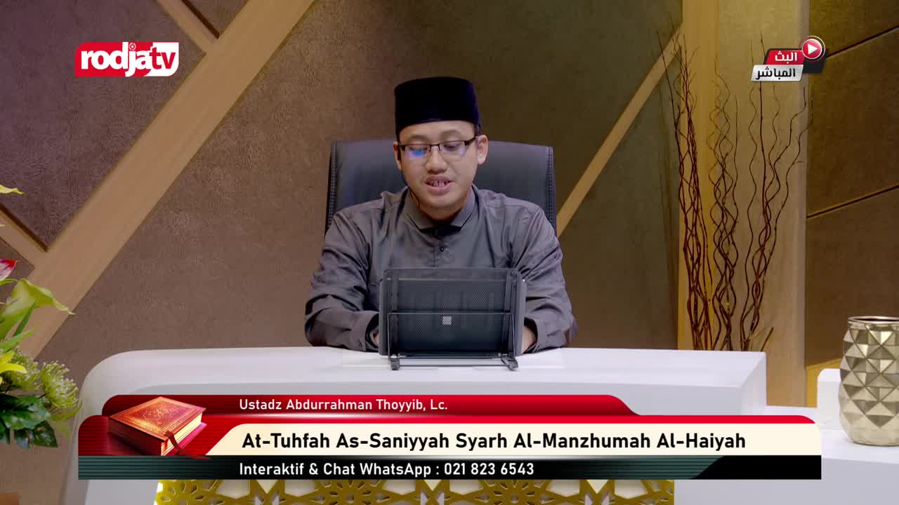 A man in a peci and glasses speaks into a tablet, his gray tunic crisp. The Rodja TV logo is visible in the corner, and Arabic text indicates a live broadcast.