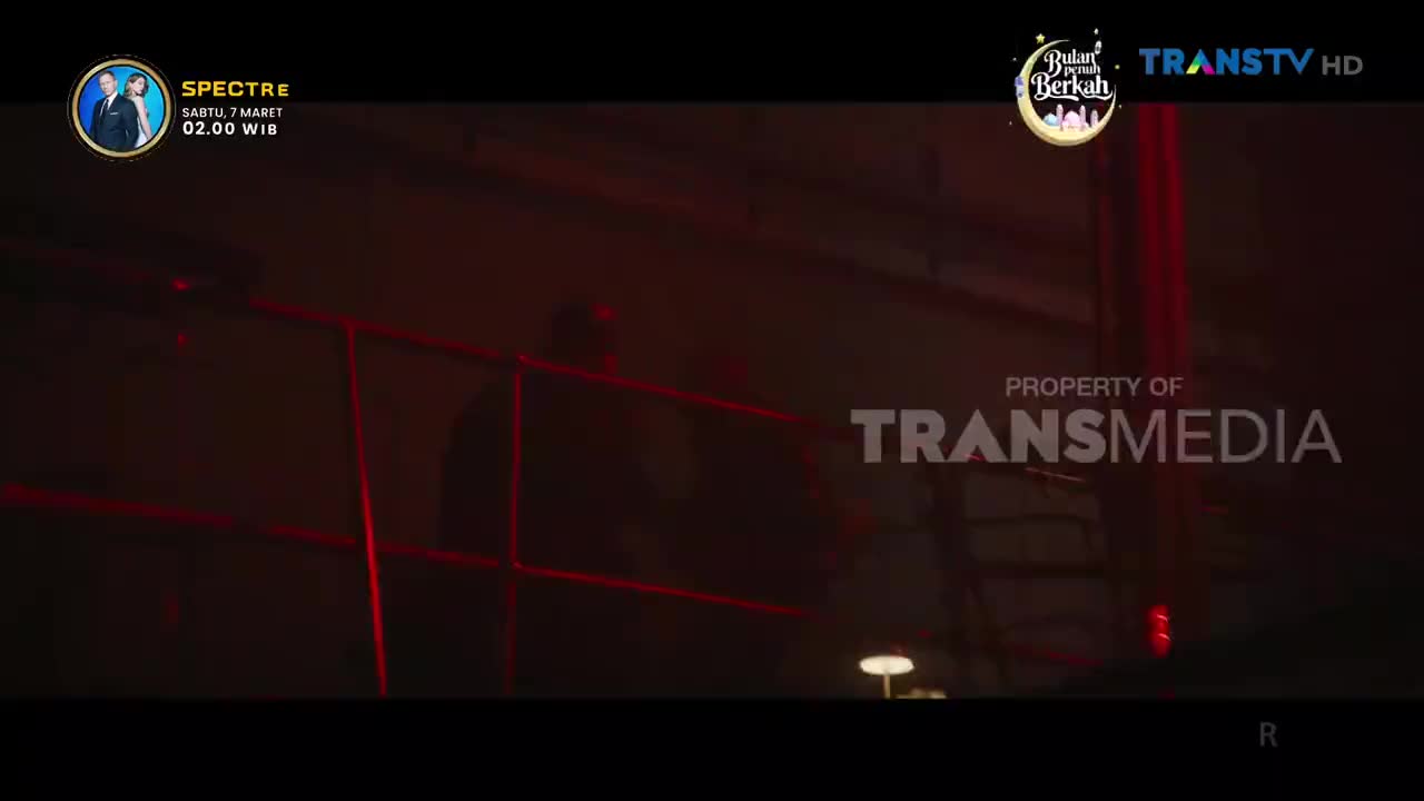 Red lights streak across a dark, industrial space, illuminating the Transmedia logo. A film titled "Spectre" is scheduled to air on Trans TV this Saturday at 2:00 AM WIB.