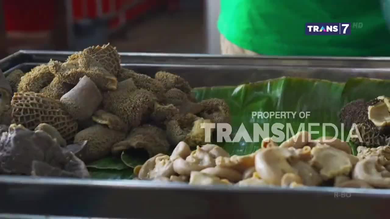 A vendor is presenting a tray of Indonesian tripe dishes, some with a honeycomb texture, others more tubular. A green Trans7 logo appears in the upper right corner. A vendor is presenting a tray of Indonesian tripe dishes, some with a honeycomb texture, others more tubular. A green Trans7 logo appears in the upper right corner.