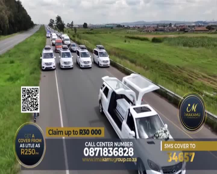 A long procession of white vehicles, including hearses and vans, travels down the highway. The lead hearse carries a coffin, its glass roof open to the sky. A long procession of white vehicles, including hearses and vans, travels down the highway. The lead hearse carries a coffin, its glass roof open to the sky.