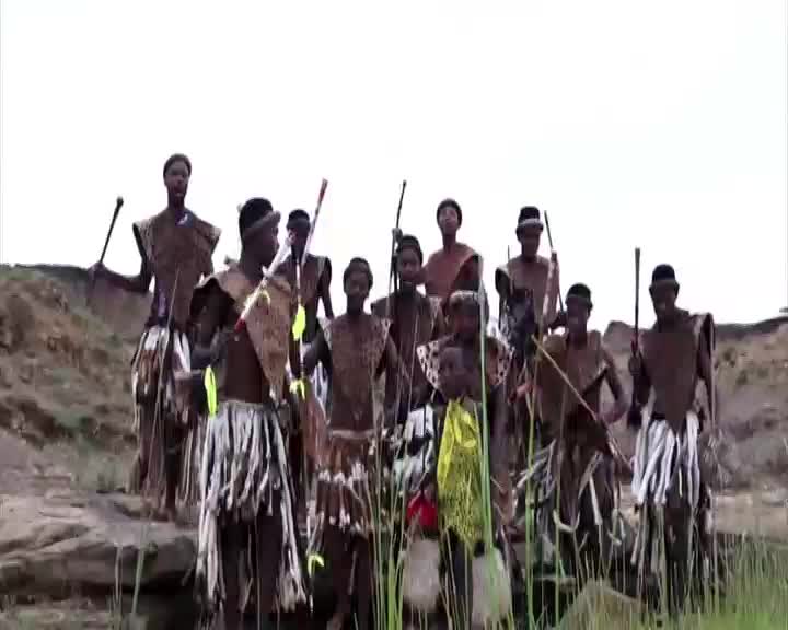 A group of men and boys, dressed in traditional Zulu attire, stand together holding spears and clubs. They are gathered on a rocky, grassy embankment, likely in KwaZulu-Natal, for a cultural display. A group of men and boys, dressed in traditional Zulu attire, stand together holding spears and clubs. They are gathered on a rocky, grassy embankment, likely in KwaZulu-Natal, for a cultural display.