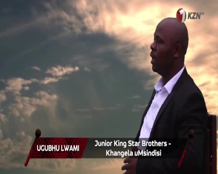 A man in a suit looks up at the sky, his mouth open as if singing. The KZN TV logo sits above his head against a dramatic cloudy backdrop.