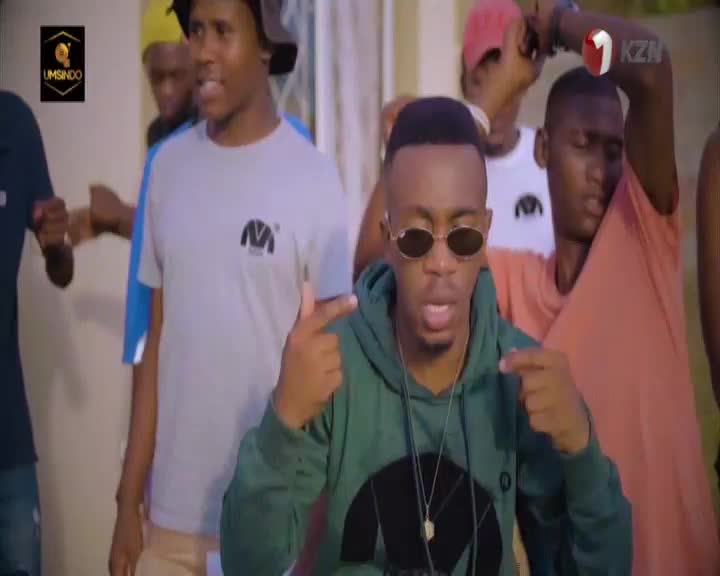 A young man in a green hoodie and sunglasses points at the camera, his friends gathered behind him. The 1KZN TV logo appears in the corner, hinting at a broadcast from KwaZulu-Natal.