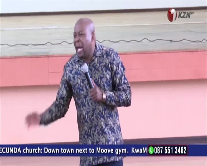 A man in a patterned shirt speaks into a microphone, gesturing with his left hand. The KZN TV logo appears in the upper right corner.