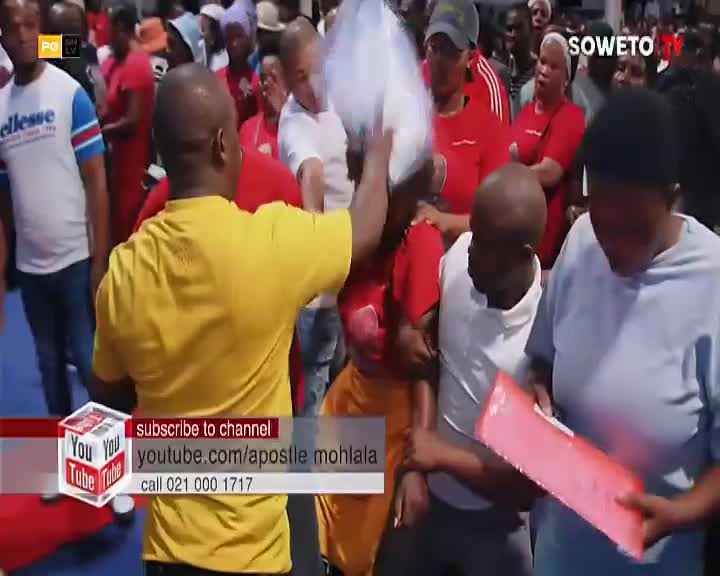 A man in a yellow shirt lifts a white bag over his head, pushing through a crowd gathered in Soweto. A woman in a blue top clutches a pink folder, her gaze fixed on something in front of her.