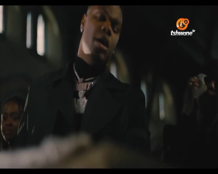 A man in a black coat and diamond chains stands with his head tilted back, singing. The Tshwane TV logo appears in the upper right corner. A man in a black coat and diamond chains stands with his head tilted back, singing. The Tshwane TV logo appears in the upper right corner.