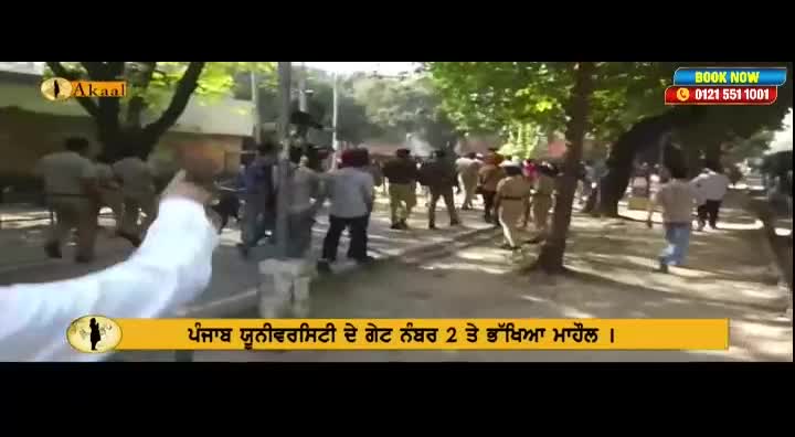 A group of uniformed individuals are moving down a tree-lined street, some appearing to be in pursuit of others. The scene is being broadcast by Akaal Channel, with a phone number for booking visible in the corner.
