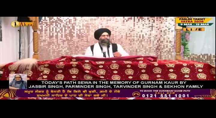 A man in a turban speaks from behind a decorated table, the Akaal Channel logo visible in the corner. The screen displays information about a Path Sewa event, live from the United Kingdom.
