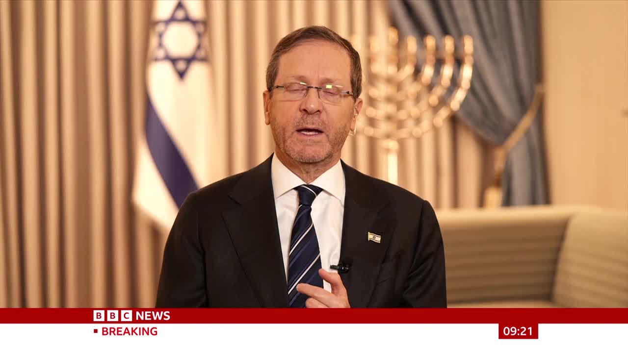 The man in the suit is speaking, gesturing with his right hand. Behind him, an Israeli flag hangs next to a menorah. A BBC News ticker runs along the bottom of the screen. The man in the suit is speaking, gesturing with his right hand. Behind him, an Israeli flag hangs next to a menorah. A BBC News ticker runs along the bottom of the screen.