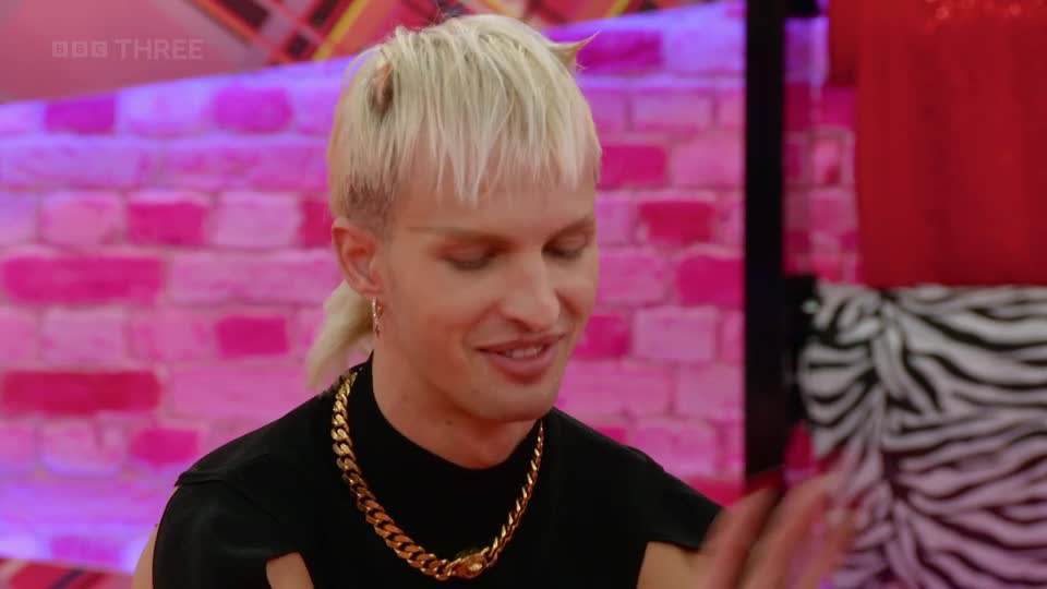 The contestant on BBC Three's show smiles, a thick gold chain around their neck. Their blonde hair is styled with a short fringe and a small ponytail. The contestant on BBC Three's show smiles, a thick gold chain around their neck. Their blonde hair is styled with a short fringe and a small ponytail.