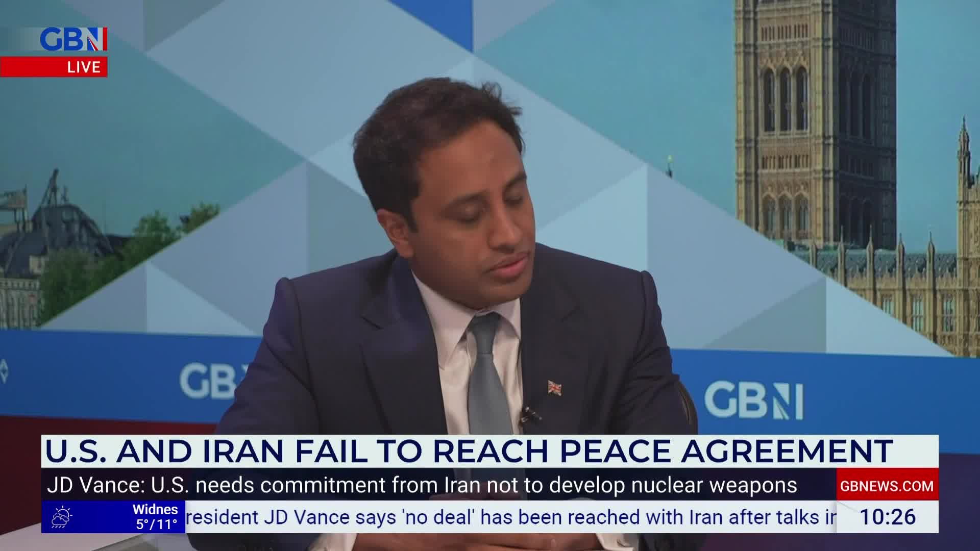 A man in a suit is speaking on GB News, with a backdrop of the Houses of Parliament. A news ticker at the bottom of the screen reports on U.S. and Iran failing to reach a peace agreement.