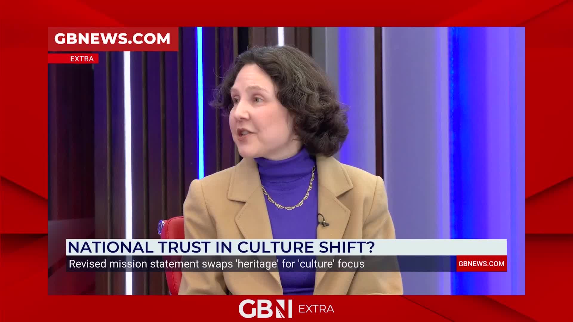 A woman in a tan coat speaks animatedly on the GB News set. The screen displays text about a National Trust culture shift.