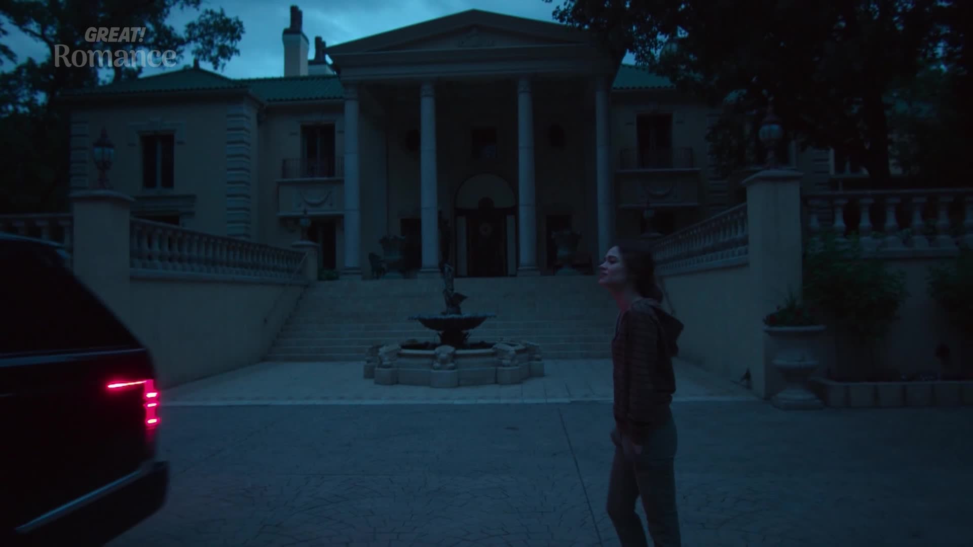 A dark SUV pulls up to a grand, neoclassical house as a young woman looks up at the sky. The twilight sky casts a moody blue over the scene, hinting at a dramatic Great! Romance unfolding.