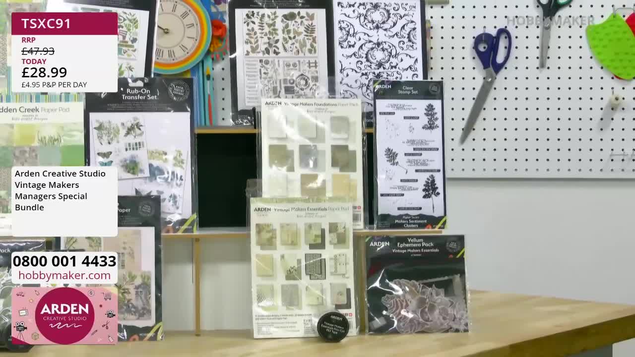 A display of craft supplies, including rub-on transfers and patterned paper, is laid out on a table. A pegboard behind the table holds scissors and other crafting tools. A display of craft supplies, including rub-on transfers and patterned paper, is laid out on a table. A pegboard behind the table holds scissors and other crafting tools.