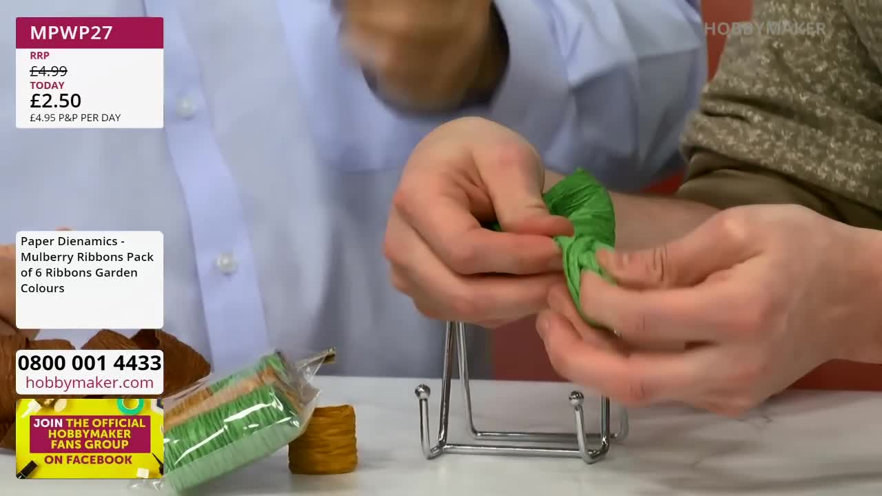 Fingers carefully pleat a vibrant green ribbon, shaping it into a delicate bloom. Nearby, a pack of six mulberry ribbons in garden colours sits ready for crafting. Fingers carefully pleat a vibrant green ribbon, shaping it into a delicate bloom. Nearby, a pack of six mulberry ribbons in garden colours sits ready for crafting.