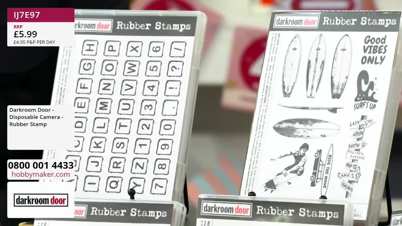 A display of Darkroom Door rubber stamps is set up, featuring a set of alphabet and number stamps on the left and a surf-themed set on the right. The hobby maker's contact information is visible on a white label. A display of Darkroom Door rubber stamps is set up, featuring a set of alphabet and number stamps on the left and a surf-themed set on the right. The hobby maker's contact information is visible on a white label.