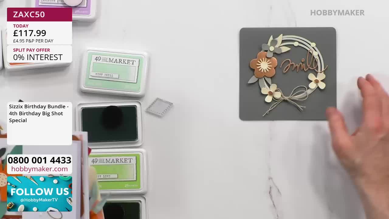 A hand reaches out towards a delicate floral wreath with the word "smile" scripted inside. Nearby, a selection of ink pads sits neatly arranged. A hand reaches out towards a delicate floral wreath with the word "smile" scripted inside. Nearby, a selection of ink pads sits neatly arranged.