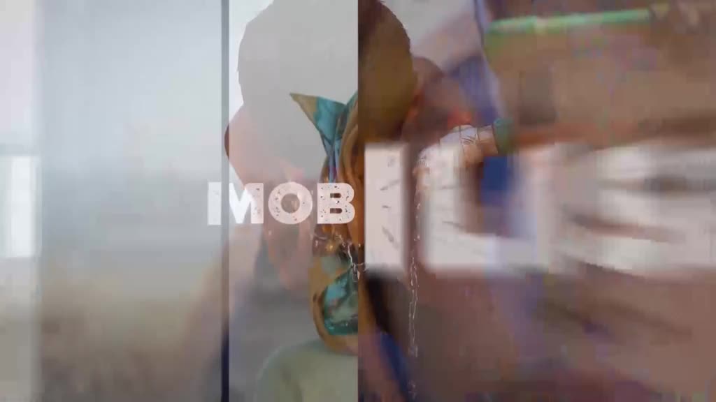 The words "IMOB" are superimposed over a woman's face, her head tilted slightly. To the right, a hand reaches for a blue object on a table, the scene blurred.