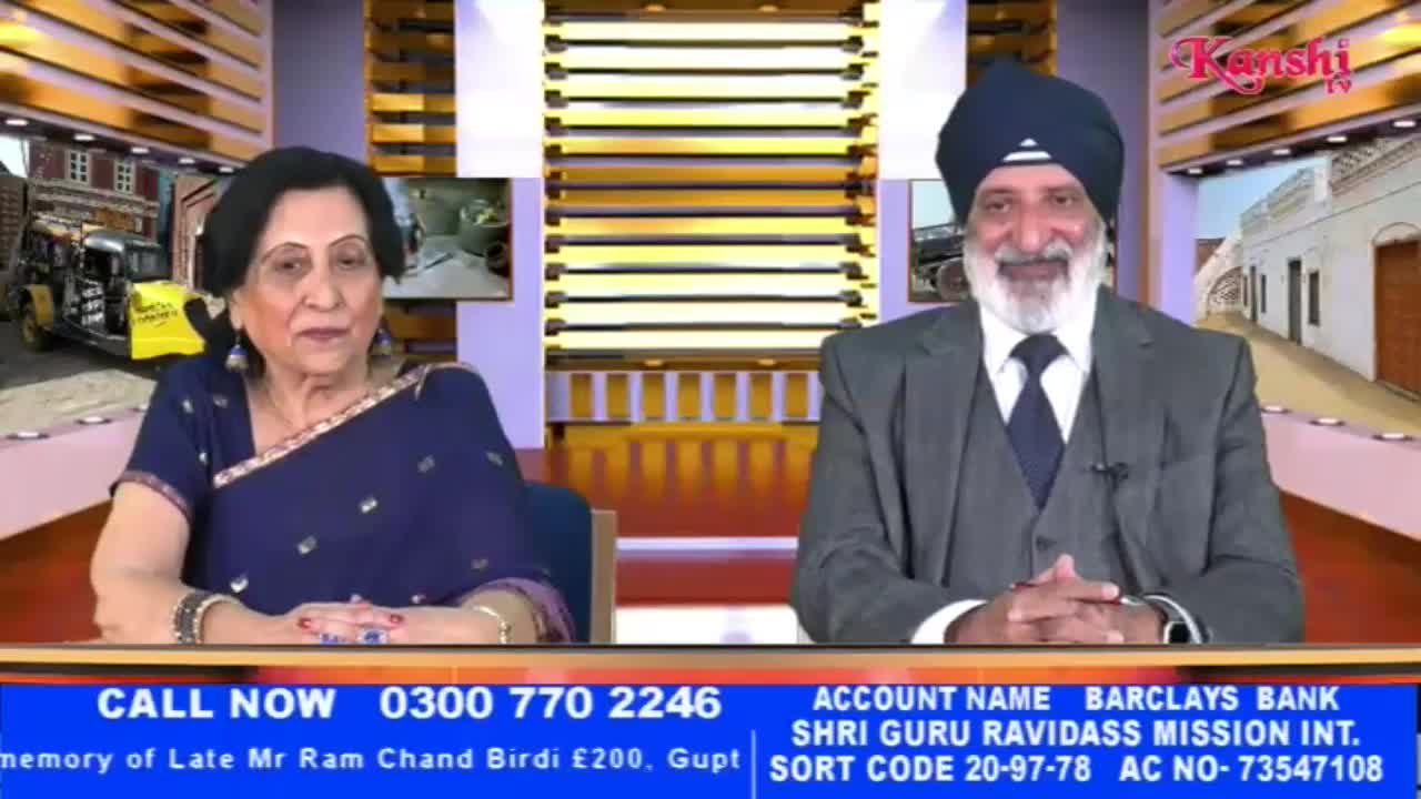 A man in a suit and turban smiles warmly, his hands clasped. Beside him, a woman in a blue sari looks thoughtfully ahead.