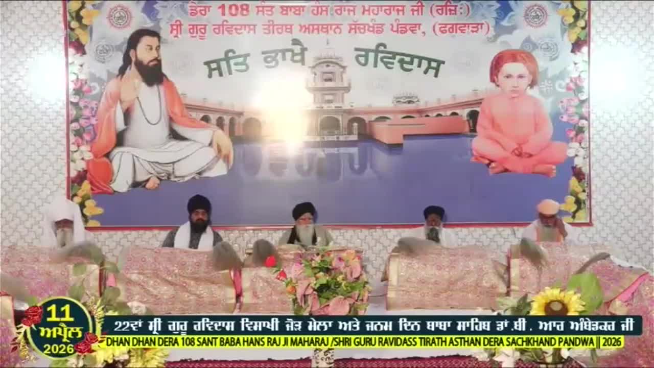 Men in turbans sit behind ornate cloths, listening intently. A large banner behind them depicts religious figures and a temple.