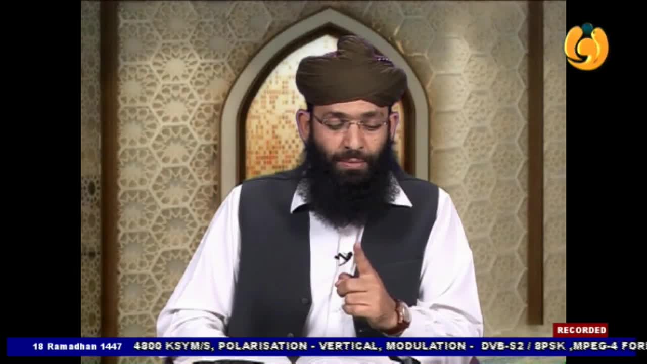 A man with a beard and glasses, wearing a turban and vest, speaks with his hand raised. The Noor TV logo appears in the corner of the screen.
