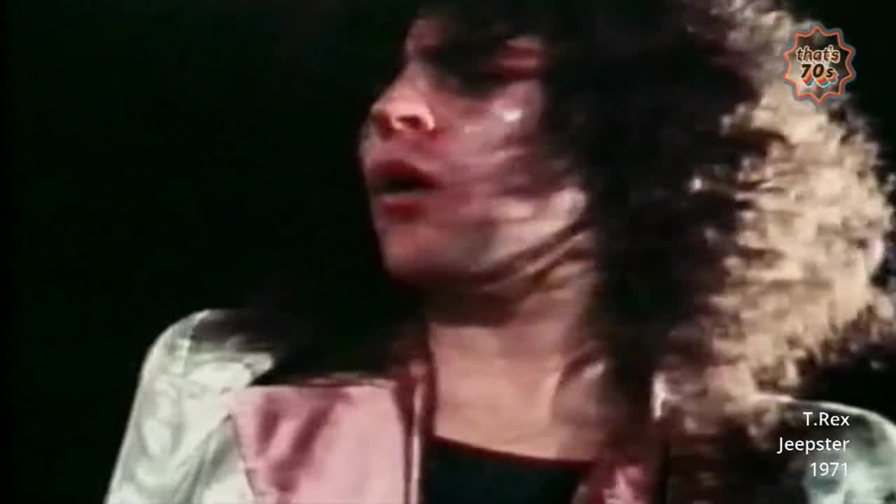 Marc Bolan's mouth hangs open, his voice raw as he belts out a line. His wild, curly hair whips around his face, a testament to the energy of the performance.