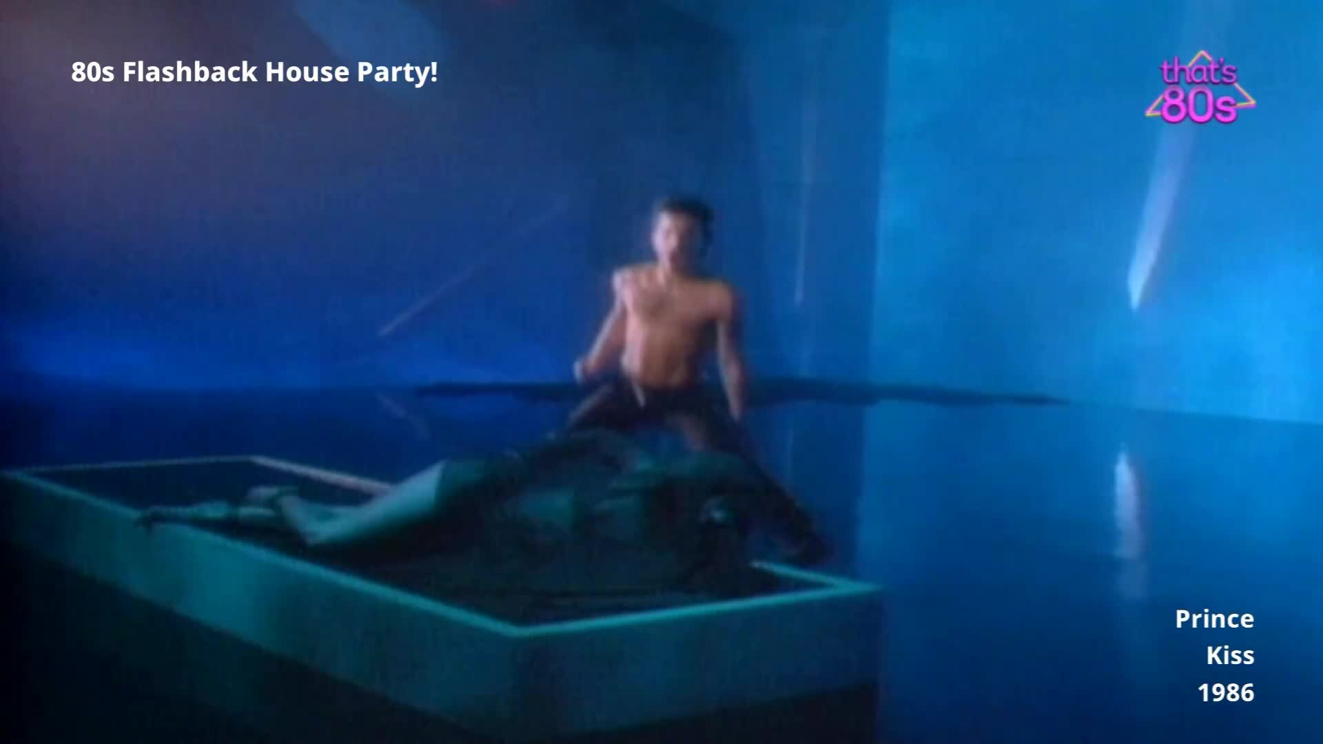 A man, shirtless and with dark hair, is perched on the edge of a raised platform. Another figure lies on the platform, partially obscured by shadow.