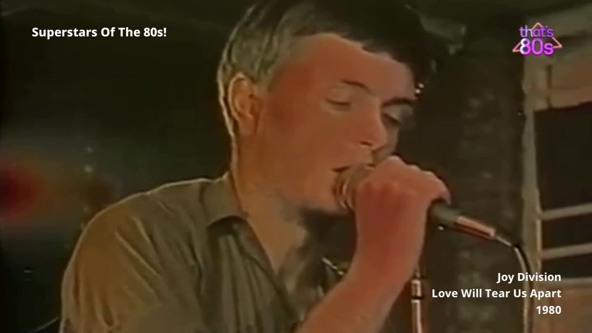 The singer leans into the microphone, his eyes closed as he belts out the lyrics. A grainy, low-light performance unfolds, capturing the raw energy of a Manchester band in 1980.