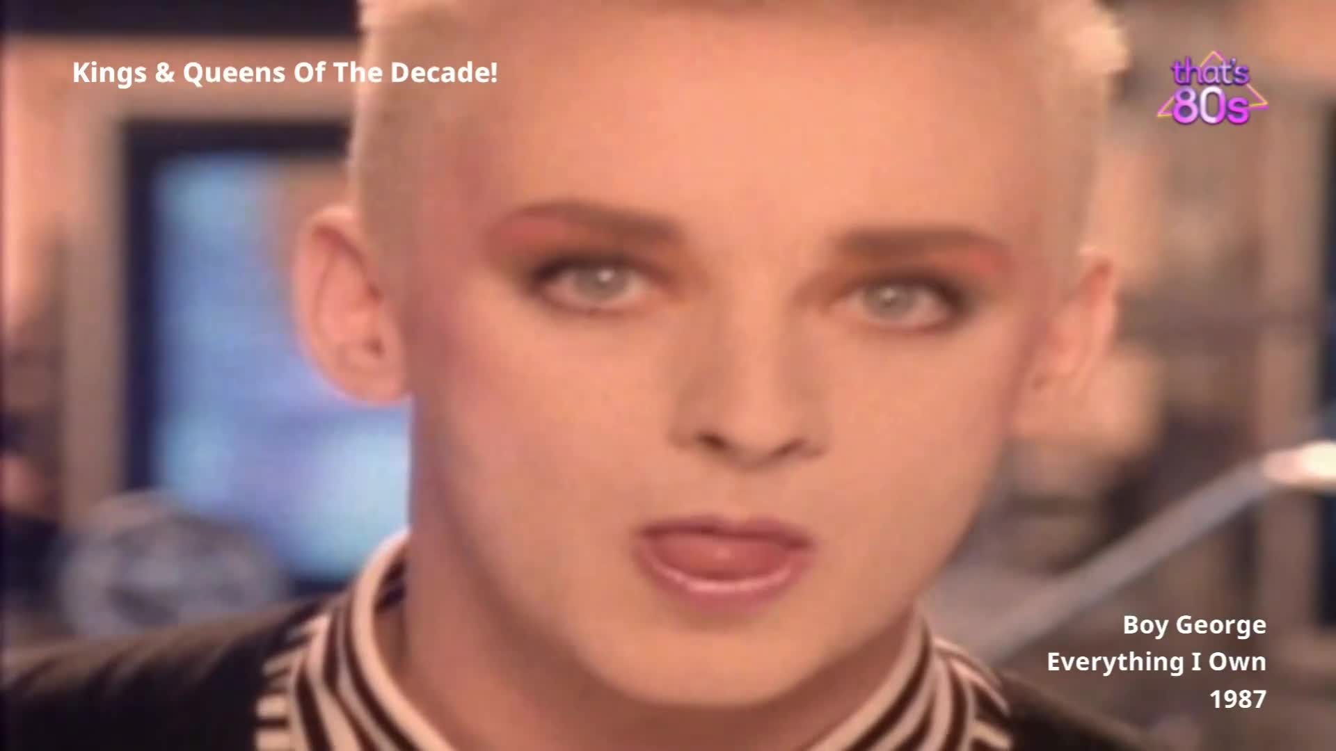 Boy George's face fills the screen, his striking blue eyes and pink eyeshadow prominent. He's wearing a black and white striped jacket, a look that screams 1980s Britain.