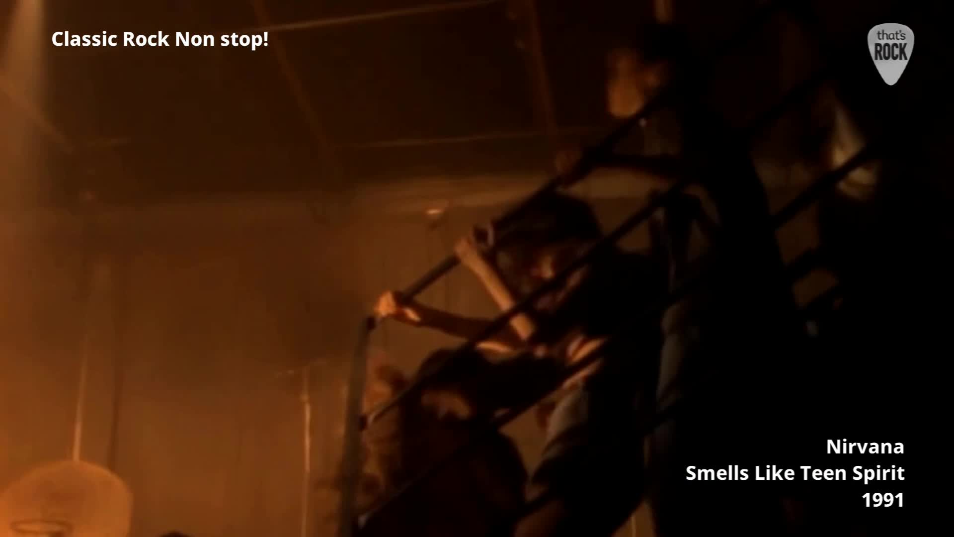 A figure grips a metal railing, their body angled as they descend a dark, spiral staircase. The air is thick with a hazy, orange light.