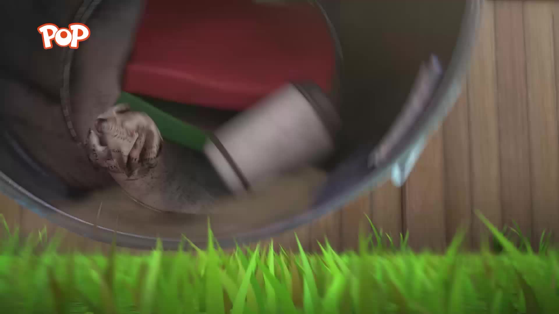 A grey, furry paw grips the edge of a wheelbarrow as it tips over. A red seat and a white cup tumble out onto the grass.