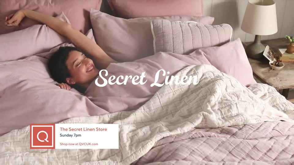 A woman stretches out in a bed covered in soft pink linens. The QVC Extra graphic indicates this is a promotion for "The Secret Linen Store" airing Sunday at 7pm. A woman stretches out in a bed covered in soft pink linens. The QVC Extra graphic indicates this is a promotion for "The Secret Linen Store" airing Sunday at 7pm.