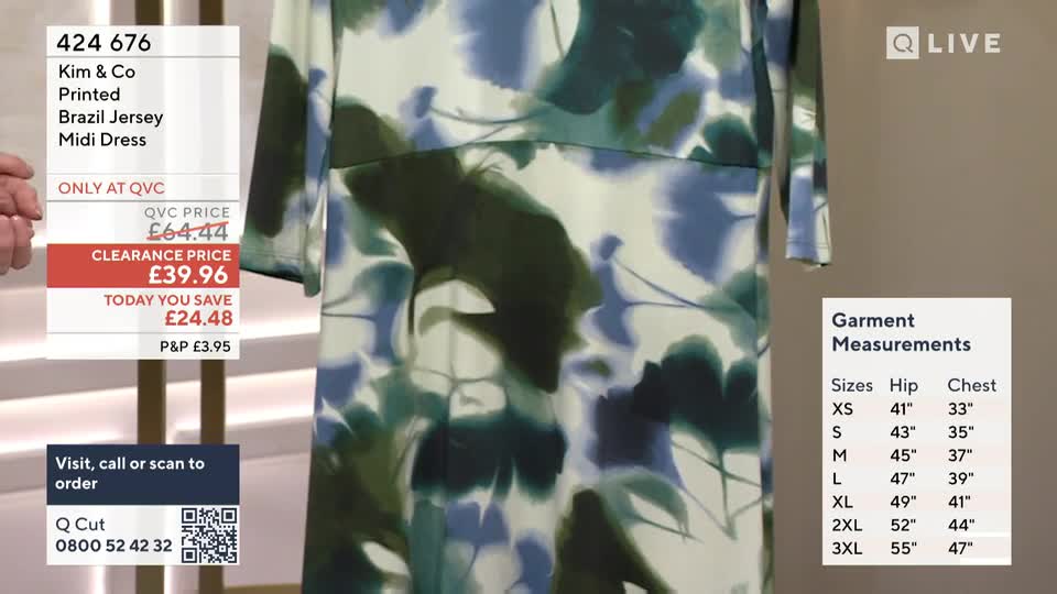A woman's hand gestures towards a QVC Extra screen displaying a floral midi dress. The screen shows the dress's original price, a clearance price of £39.96, and garment measurements. A woman's hand gestures towards a QVC Extra screen displaying a floral midi dress. The screen shows the dress's original price, a clearance price of £39.96, and garment measurements.