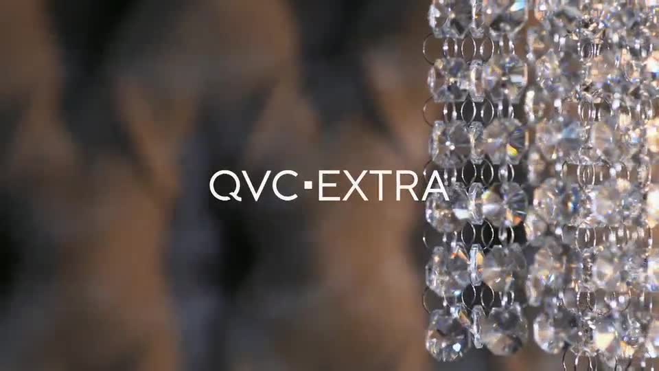 A strand of faceted crystals hangs, catching the light. The words "QVC EXTRA" appear in white text against a soft, blurred background.