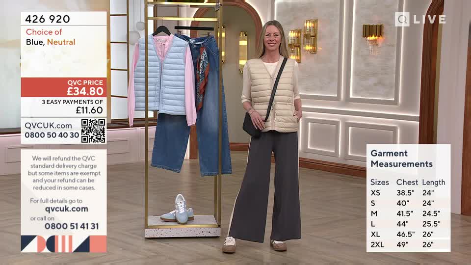 A woman stands in wide-legged grey trousers and a cream gilet, presenting an outfit on a rack. The display includes a pale blue gilet, a pink top, and denim jeans.