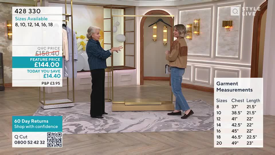 A woman in a blue denim jacket gestures towards a display rack. Another woman, wearing a tan jacket with fringe, stands facing her, listening.