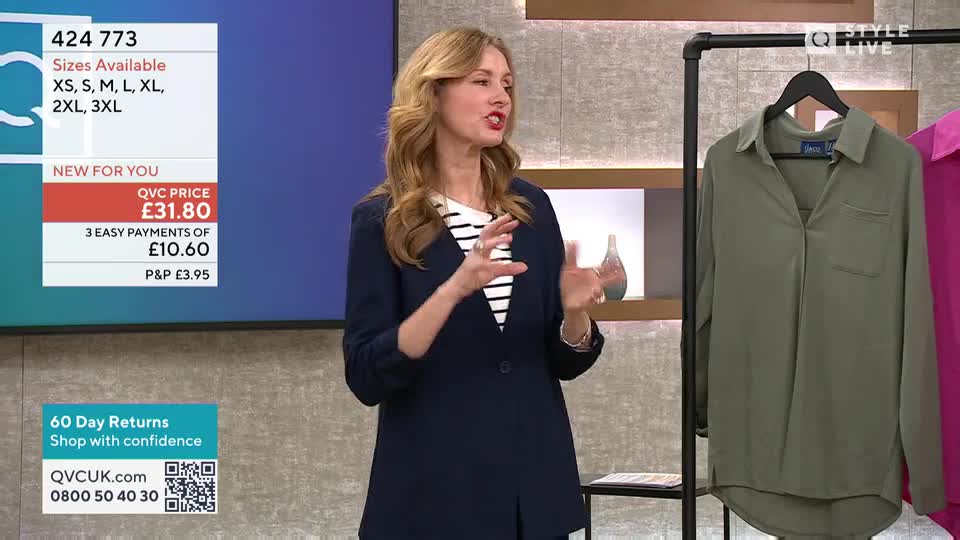 A woman in a navy blazer gestures animatedly while discussing a khaki shirt hanging on a rack. On a screen behind her, the price of the shirt is displayed along with available sizes.