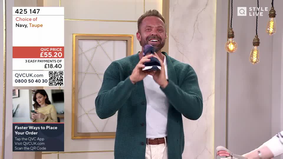 A man in a green cardigan beams as he holds up a pair of navy trainers. On the screen, the price is displayed as £55.20, with an option for three easy payments.