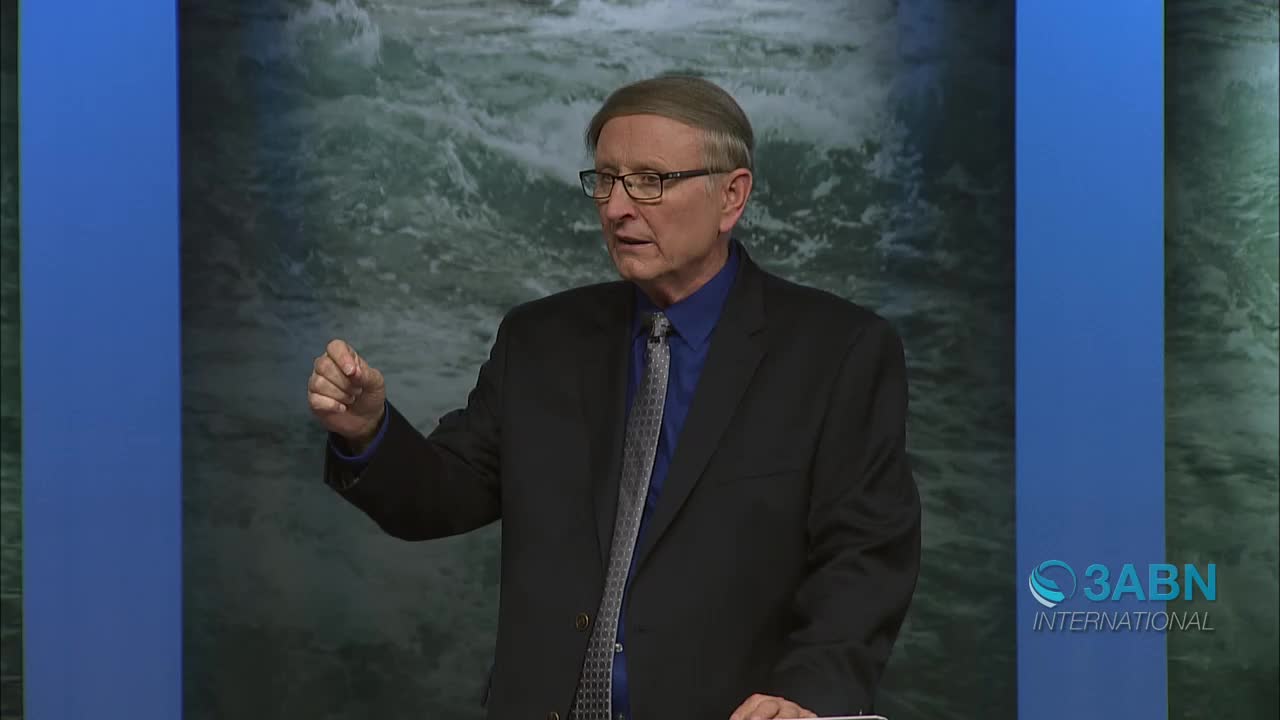 A man in a suit speaks, gesturing with his right hand. Behind him, a backdrop depicts turbulent water. The 3ABN International logo appears in the lower right corner.