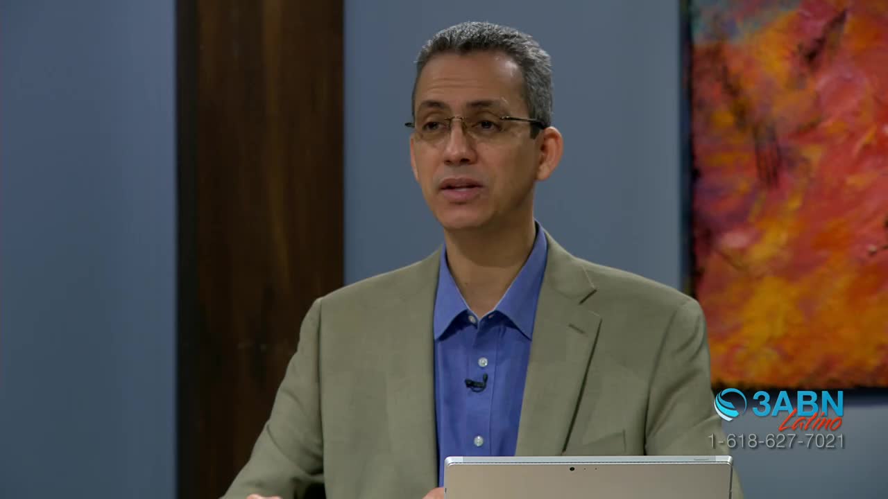A man in a tan blazer and blue shirt gestures as he speaks, a tablet in his hands. The 3ABN Latino logo is visible in the corner.
