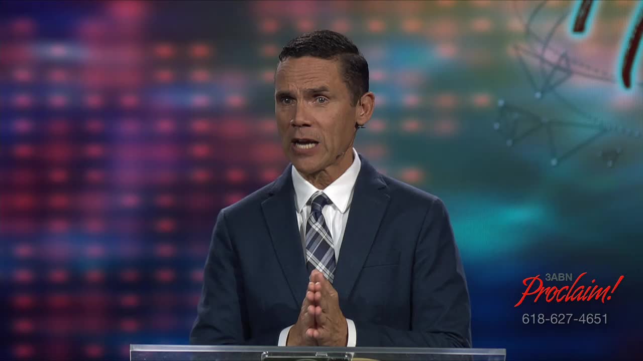 A man in a suit stands behind a clear podium, speaking with his hands clasped in front of him. The 3ABN Proclaim! logo is visible in the corner of the screen.
